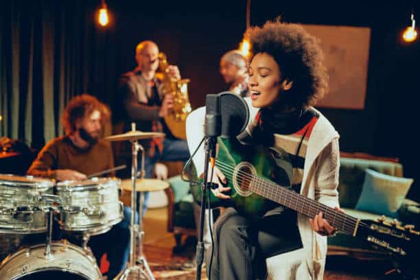 Female musician singing and playing green guitar.